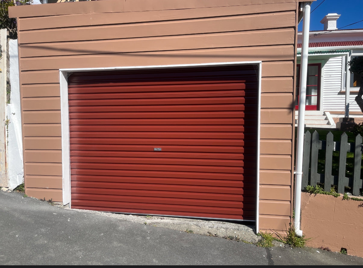 Brown garage with a red roller door on a residential street